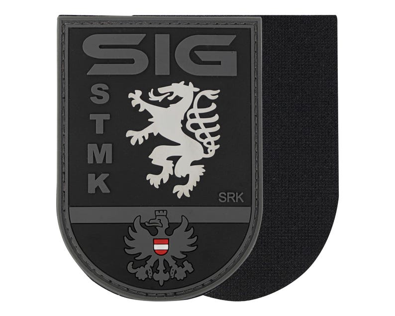 May include: A black and gray patch with the text "SIG" at the top and "STMK" vertically on the left. A white lion and a gray eagle with a red and white shield are featured. The text "SRK" is at the bottom.