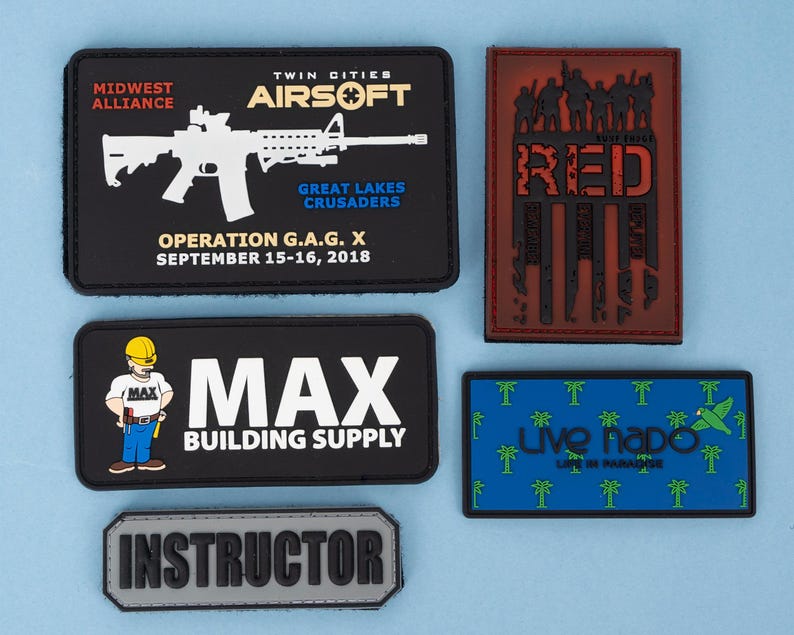 May include: A collection of rectangular patches with various designs and text. One patch features a white rifle graphic and text for "Midwest Alliance" and "Twin Cities Airsoft." Other patches include "MAX BUILDING SUPPLY," "RED," and "Instructor."