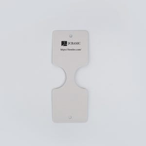 May include: A light gray, double-ended tag with a unique cutout design. The tag features the JCBASIC logo and website address. It has two small holes for attachment.