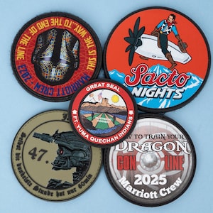 May include: A collection of five circular patches with various designs. One features a cowboy on a plane with "Sacto Nights" text. Others include text like "Marriott Crew," "Dragon Con Line 2025," and a military-themed patch with the number "47."