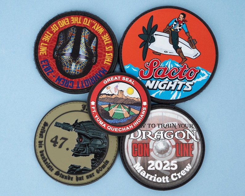 May include: A collection of five circular patches with various designs. One features a cowboy on a plane with "Sacto Nights" text. Others include text like "Marriott Crew," "Dragon Con Line 2025," and a military-themed patch with the number "47."