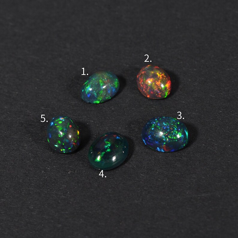 May include: Five oval-shaped black opals with iridescent green, blue, and red flashes. The opals are numbered 1 through 5.