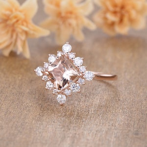 K&ouml;nnte beinhalten: Ein Verlobungsring aus Ros&eacute;gold mit einem quadratischen Morganit-Mittelst&uuml;ck, das von einem Heiligenschein aus kleineren Diamanten umgeben ist.