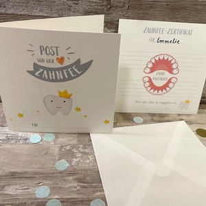 Może przedstawiać: Certyfikat wr&oacute;żki zębuszki z r&oacute;żowo-białą ilustracją ust z zębami. Certyfikat jest dla Emmelie i ma miejsce na śledzenie utraconych zęb&oacute;w.