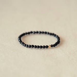 May include: A black beaded bracelet with a single gold bead accent.