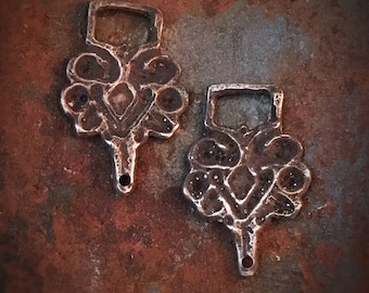 Könnte beinhalten: Zwei antike silberfarbene Metallschnallen mit aufwendigen floralen Designs. Die Schnallen haben ein kleines Loch unten und eine rechteckige Öffnung oben.