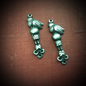 May include: Two silver-toned bird charms with detailed wings and a beaded body. The charms have a loop at the top for attaching to a necklace or bracelet.