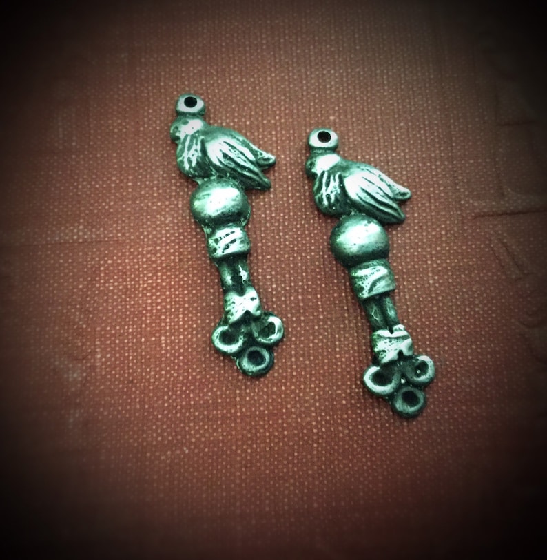 May include: Two silver-toned bird charms with detailed wings and a beaded body. The charms have a loop at the top for attaching to a necklace or bracelet.