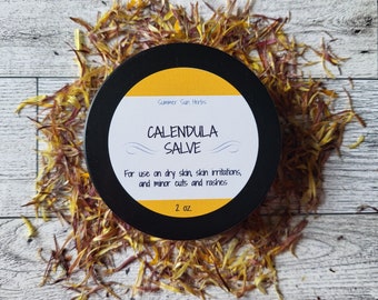 May include: A black jar with a white label that reads "Summer Sun Herbs Calendula Salve" and "For use on dry skin, skin irritations, and minor cuts and rashes 2 oz."