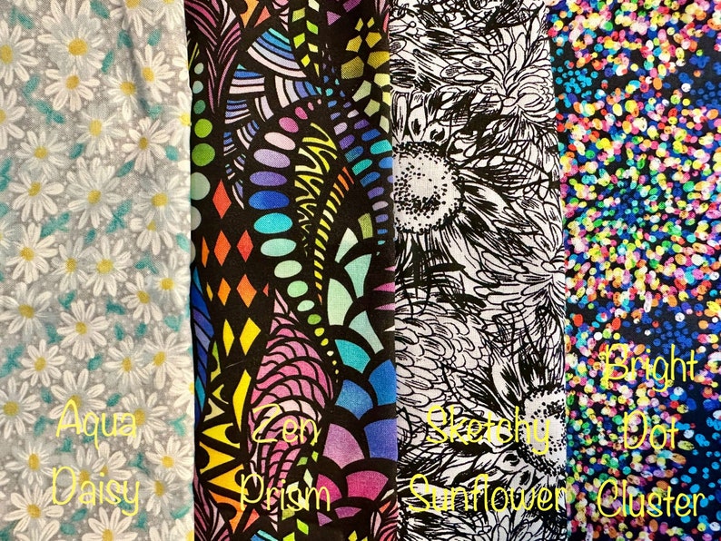 May include: Four fabric swatches with different patterns. The first swatch is a light blue fabric with a white daisy pattern. The second swatch is a black fabric with a colorful abstract pattern. The third swatch is a white fabric with a black and white sunflower pattern. The fourth swatch is a dark blue fabric with a colorful confetti pattern.