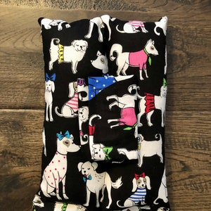May include: Black fabric tissue box cover with a white and black dog pattern. The dogs are wearing colorful accessories like bows, hats, and scarves.