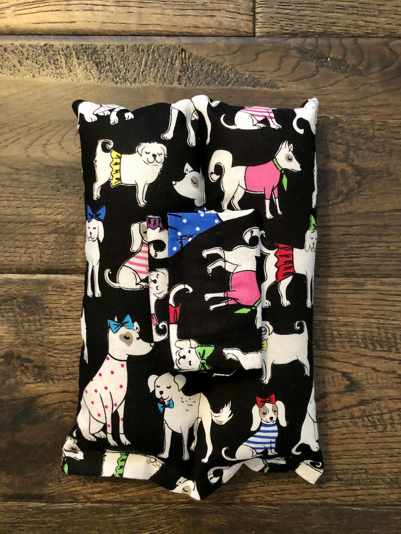 May include: Black fabric tissue box cover with a white and black dog pattern. The dogs are wearing colorful accessories like bows, hats, and scarves.