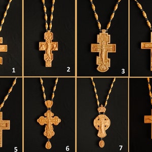 May include: Eight wooden crosses with intricate carvings, each on a beaded chain. The crosses feature various religious symbols and figures, including a crucifix and a crown.