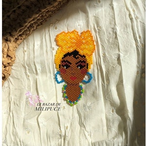 Peut inclure: Portrait en perles d'une femme portant un foulard jaune et des boucles d'oreilles bleues. La femme porte un collier de perles multicolores. Le portrait est réalisé avec de petites perles et est très détaillé.