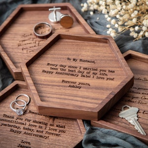 May include: A set of three hexagonal wooden trays with engraved messages. The trays are made of dark wood and have a natural finish. The messages on the trays are: "To My Husband, Every day since I married you has been the best day of my life. Happy Anniversary Babe! I love you! Forever yours, Ashley", "Thank you for showing me what unconditional love is. I love you yesterday, today, and forever. Happy Anniversary! Love, Jasper", and "Bride Sa her perso entuses and you. Car attas! Here".