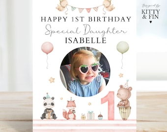 May include: A pink and white birthday card with a photo of a young girl wearing sunglasses. The card says "Happy 1st Birthday Special Daughter Isabelle" and features a number one, a panda, a fox, and a bear.