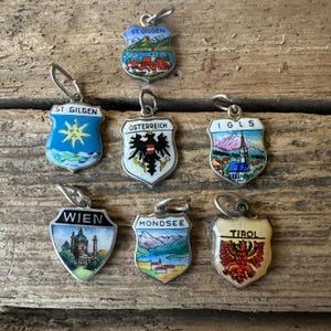 May include: Seven silver charm pendants with enamel designs depicting Austrian cities and regions. The charms feature images of St. Gilgen, Austria, Innsbruck, Mondsee, Tyrol, Vienna, and Igls.