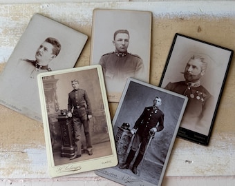 Puede incluir: Una colección de cinco fotografías de retratos antiguos que muestran a hombres con uniformes militares. Las imágenes son en blanco y negro y tonos sepia, con diferentes poses y fondos. Algunas fotos tienen marcas de estudio.