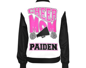 May include: White and black bomber jacket with pink lettering that says "Cheer Mom" and a black megaphone graphic. The name "Paiden" is printed in pink below the graphic.