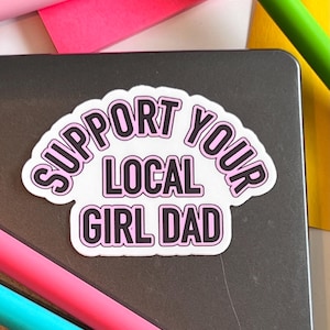 Puede incluir: Una pegatina blanca con letras rosas que dice "Support Your Local Girl Dad".