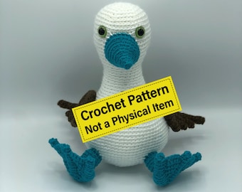 May include: Crocheted blue-footed booby amigurumi toy. The toy is white with blue feet and a blue beak. The toy is holding a yellow sign that says "Crochet Pattern Not a Physical Item".