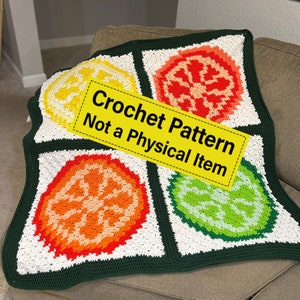 Könnte beinhalten: Eine grüne, weiße, gelbe, orangefarbene und limettengrüne Häkeldecke mit quadratischem Design, das vier verschiedene Fruchtmotive zeigt. Die Decke liegt auf einem braunen Sofa. "Crochet Pattern Not a Physical Item" steht in Gelb auf schwarzem Hintergrund.