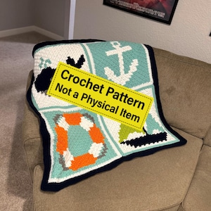 May include: A nautical-themed crochet blanket with a white, teal, and navy blue color scheme. The blanket features square panels with an anchor, life preserver, and sailboat designs. The text on the yellow sign reads "Crochet Pattern Not a Physical Item."