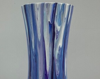 May include: A tall, decorative vase with a flared base and a slightly wider top. The vase features a flowing, abstract design in shades of blue, white, and purple. The paint appears to have been poured and swirled, creating a unique pattern.