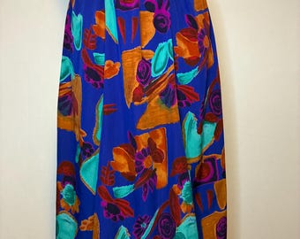 Könnte beinhalten: Ein wadenlanger Rock mit einer leuchtend königsblauen Grundfarbe und einem abstrakten Muster aus orangefarbenen, türkisfarbenen und dunkelvioletten Formen. Der Rock hat einen elastischen Bund und eine fließende, lockere Silhouette.