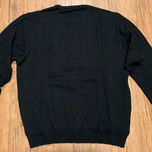 Peut inclure: Un pull noir &agrave; manches longues avec un col rond.