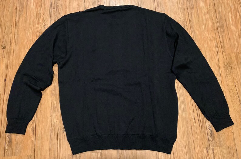 Peut inclure: Un pull noir &agrave; manches longues avec un col rond.