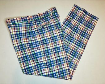 Könnte beinhalten: Eine Hose mit einem mehrfarbigen Karomuster in Blau, Grün, Weiß und Orange. Die Hose verfügt über einen Bund mit Gürtelschlaufen, einen Knopfverschluss auf der Vorderseite und eine sichtbare Tasche auf der rechten Vorderseite des Kleidungsstücks.