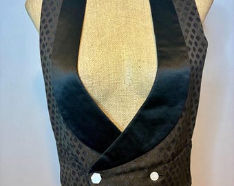 Könnte beinhalten: Eine braune Weste mit schwarzem Satin-Schalkragen und drei weißen Knöpfen. Die Weste hat ein sich wiederholendes Rautenmuster und wird auf einer Schaufensterpuppe präsentiert.