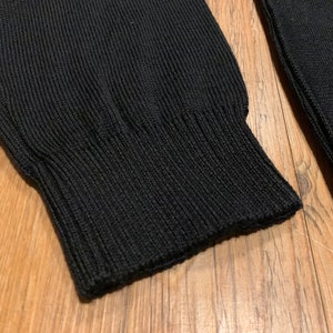 Peut inclure: Gros plan sur la manchette en tricot c&ocirc;tel&eacute; noir d'un pull.