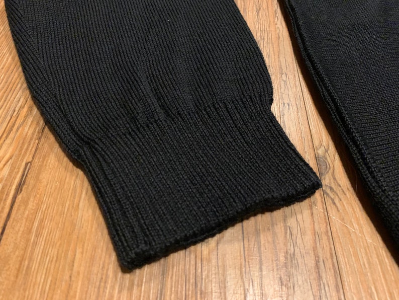 Peut inclure: Gros plan sur la manchette en tricot c&ocirc;tel&eacute; noir d'un pull.