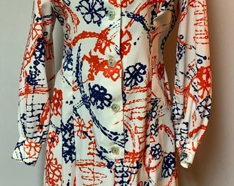 Puede incluir: Vestido blanco vintage con botones en la parte delantera, mangas largas y cuello camisero. El vestido presenta un estampado llamativo de formas florales y geométricas abstractas en rojo y azul marino.