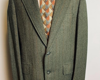 May include: A green herringbone blazer with a single button closure. The blazer has a pointed collar and a chest pocket.