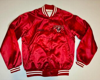 Könnte beinhalten: Eine rote Satin-Collegejacke mit langen Ärmeln, Druckknopfleiste und weiß gestreiften Rippbündchen an Kragen, Ärmeln und Saum. Auf der Brust befindet sich der gestickte Name Belinda sowie ein Louisville-Logo mit einer Vogel-Maskottchen-Grafik.