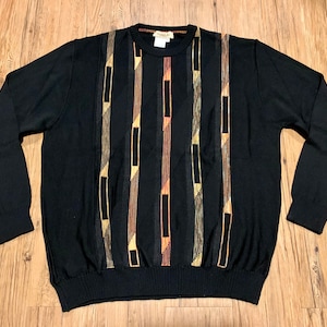 Peut inclure: Pullover noir &agrave; manches longues avec un motif g&eacute;om&eacute;trique en marron, or et orange.