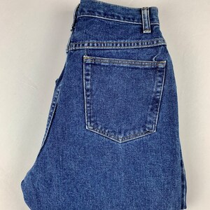 May include: A pair of blue denim jeans folded in half. The jeans have a back pocket and a button fly.