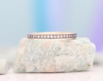 May include: A delicate gold band with a row of small, sparkling diamonds set in a pave setting.