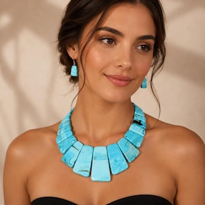 Peut inclure: Un collier turquoise imposant et des boucles d'oreilles assorties. Le collier présente de grandes pierres turquoises rectangulaires avec un effet marbré. Les boucles d'oreilles sont de petites pierres turquoises rectangulaires. Les bijoux sont portés sur un fond neutre.