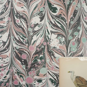 May include: A close-up of marbled paper with a swirling pattern of black, white, pink, and green. The paper is textured and has a vintage look.