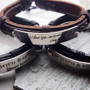 May include: Two leather bracelets with engraved metal plates. One plate reads "love you so much" and the other reads "45°54′15″N 68°55′17″ Mount Katahdin" and "34°33′27″N 84°15′08″ where it all began".