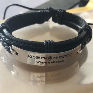 May include: Black leather bracelet with a silver plate engraved with the coordinates "40.5551°N 75.9825°W" and the text "Where it all began".