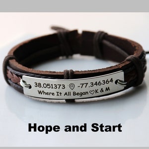 Puede incluir: Pulsera de cuero marrón con una placa plateada grabada con las coordenadas 38.051373 -77.346364 y el texto "Where It All Began" con un símbolo de corazón y las iniciales "K & M".