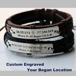 May include: Two leather bracelets with engraved metal plates. The top bracelet is brown leather with a silver plate that reads "38.051373 -77.346364 Where It All Began♡K & M". The bottom bracelet is black leather with a silver plate that reads "46°36'14.9''N 120°29'53.5''W Where it all began".