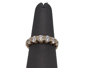 May include: A gold band ring with a row of round clear stones.