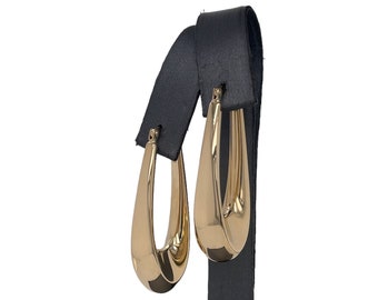 May include: A pair of gold hoop earrings with a teardrop shape. The earrings are displayed on a black stand.