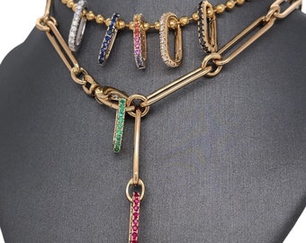 May include: A gold chain necklace with a dangling charm featuring a row of red gemstones. Five hoop earrings with rows of gemstones in various colors are displayed on a mannequin.